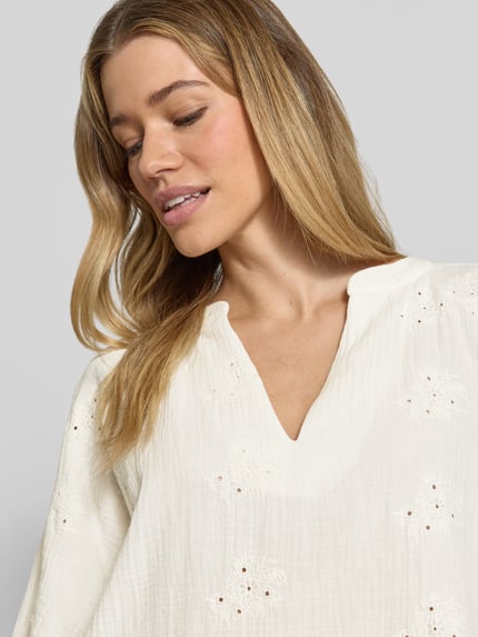 Vrouwenmodel draagt Relaxed Fit langarmblouse uit pure katoen model 'NATALI' van Vero Moda, effen, V-hals, seersucker, detailopname bovenlichaam.