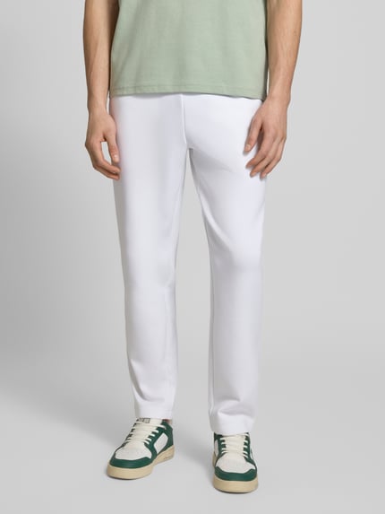 Mannenmodel draagt Tapered Sweatpants met katoen van Lacoste Sport, wit, scuba-materiaal, logo-patch, unicolor, tapered fit, vooraanzicht heup-nahaufnahme.
