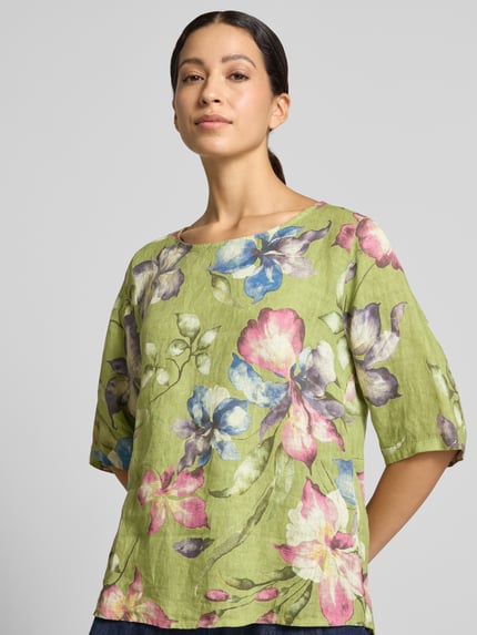 Frauenmodel trägt Leinenbluse aus reinem Leinen Modell 'Rileyy' von ZABAIONE in grün mit buntem Blumenmuster, lockere Passform, Nahaufnahme Oberkörper.
