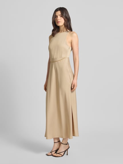 Frauenmodel trägt Maxikleid mit Ketten-Detail von ARMANI EXCHANGE aus beigefarbenem Satin, taillierter Schnitt, Ganzkörperansicht von vorne.
