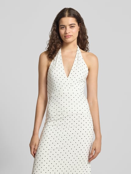 Frauenmodel trägt Slim Fit Top mit Neckholder von Gina Tricot in Weiß mit schwarzen Punkten, Elastischer-Material-Mix, V-Ausschnitt, Rückenlänge bei Größe S: 58 cm, Ganzkörperansicht von vorne.