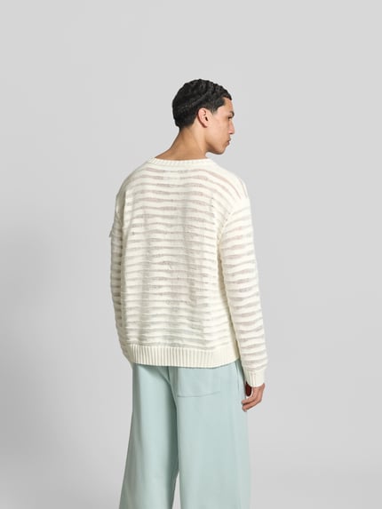 Męski model nosi Relaxed Fit Pullover in Strick-Optik od MM6 Maison Margiela, bawełna, krój relaxed fit, okrągły dekolt, elastyczne wykończenia, długość tyłu w rozmiarze M: 67 cm, jasne kolory, proste paski, tekstura dzianiny, całopostaciowy widok z tyłu.