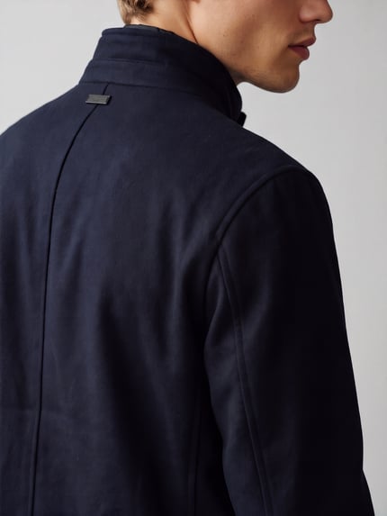 Männermodel trägt Mantel aus Wolle mit Stehkragen Modell 'Finlay 2.0' von STRELLSON in dunklem Melange, Struktur, Detailaufnahme Rückansicht.