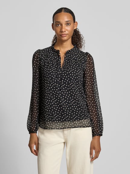 Frauenmodel trägt Regular Fit Langarmbluse mit Bindeverschluss Modell 'DITSY' von ONLY, schwarze Bluse mit weißen Punkten, Damen Langarmbluse von ONLY, Ganzkörperansicht von vorne.