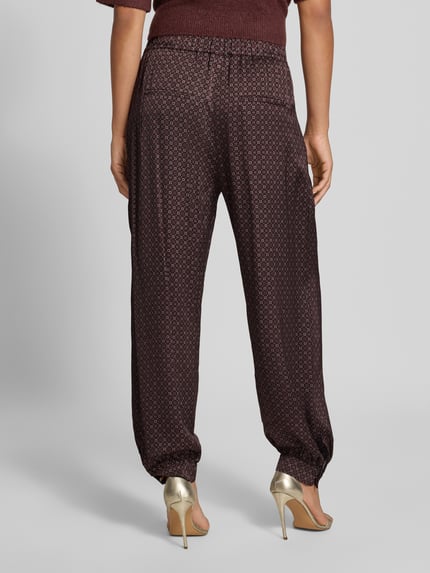Frauenmodel trägt Loose Fit Weite Hose mit Allover-Muster von Jake*s aus der Jake*s Collection in dunklem Rot mit kleinen Mustern, Ganzkörperansicht Rückansicht.