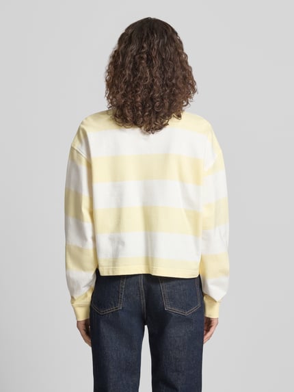 Vrouwenmodel draagt Relaxed Fit Sweatshirt met Logo-Stitching model 'Varsity' van Calvin Klein Jeans in zachtgeel-witte strepen, pure katoen, elastische mouwboorden, lange mouwen, knoopsluiting, ruglengte maat S: 50 cm. Volledige lichaamsaanzicht achterkant.
