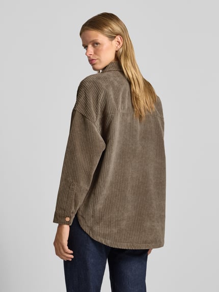 Frauenmodel trägt Oversized Hemdjacke mit verdecktem Druckknopfverschluss Modell 'JANINE-RAI' von ONLY in Beige mit feiner Cordstruktur, Ganzkörperansicht Rückansicht, Damen Hemdjacke von ONLY.