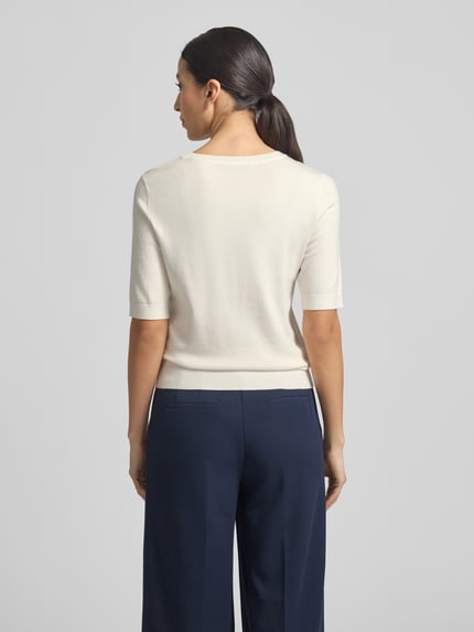 Modelka kobieca ma na sobie Strickshirt aus Viskose-Mix mit Rundhalsausschnitt od Betty Barclay, biały, krój regular fit, 1/2-rękaw, widok całej sylwetki z tyłu.