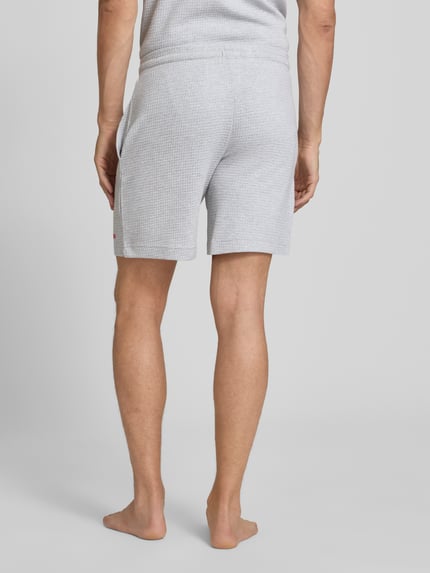 Männermodel trägt Regular Fit Sweatshorts aus Baumwoll-Mix Modell 'AUSTIN' von HUGO, hellgrau, strukturierte Oberfläche, Ganzkörperansicht Rückansicht, Herren Sweatshorts von HUGO.