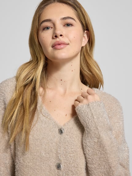 Vrouwenmodel draagt Strickjacke aus Effektgarn mit V-Ausschnitt Modell 'LISTRA' van YAS in beige met knoopsluiting, regular fit, viscosemix, detailopname bovenlichaam.