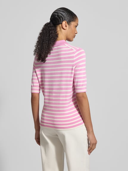 Frauenmodel trägt Poloshirt aus Viskose-Mix von Christian Berg Woman, rosa-weiß gestreift, gerader Schnitt, 1/2-Arm, Ganzkörperansicht Rückansicht.