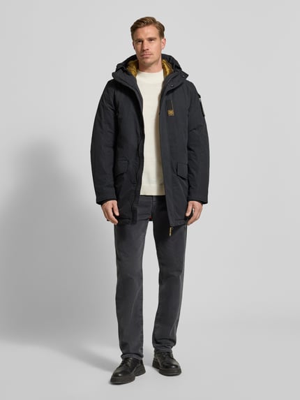 Männermodel draagt Parka met Label-Detail van PME Legend in regular fit, donkerkleurig met capuchon en klepzakken, Ganzkörperansicht von vorn.