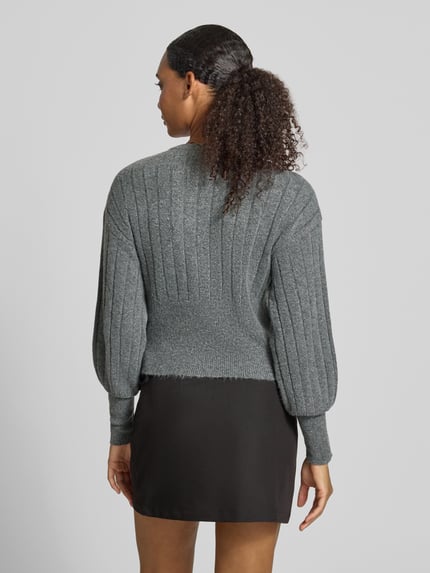 Frauenmodel trägt Strickjacke mit Rundhalsausschnitt Modell 'NOELLA' von NOISY MAY®, grau, gerippte Textur, Rückenansicht, Ganzkörperansicht. Material-Mix mit Stretch-Anteil, Slim Fit.