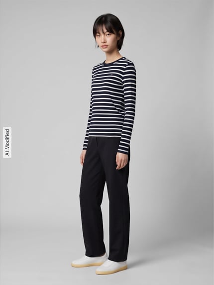 Frauenmodel trägt Slim Fit Langarmshirt aus reiner Baumwolle von Tommy Hilfiger, schwarz-weiß gestreift, kombiniert mit dunkler Hose, Ganzkörperansicht von vorne, Damen Langarmshirt von Tommy Hilfiger, KI-modifiziertes Bild.