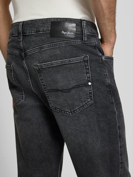 Männermodel trägt Regular Fit Straight Jeans aus Baumwoll-Lyocell-Mix Modell 'CASH' von Pepe Jeans in denimlook met labelpatch en label in reliëf, 5-pocketmodel, knoop- en ritssluiting, riemlussen, twill-materiaalverwerking, detailaufnahme achterzijde.