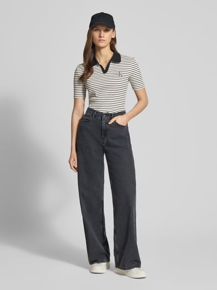 Vrouwenmodel draagt Slim Fit Poloshirt met Labelstitching van Calvin Klein Jeans, mix van katoen en elastaan, V-hals, riblook, ruglengte maat S 55 cm, volledige lichaamsvoorzijde.
