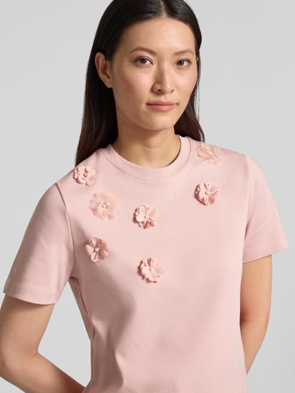 Frauenmodel trägt T-Shirt mit floralen Applikationen von Christian Berg Woman in Rosa, Reine Baumwolle, Gerader-Schnitt, Rundhalsausschnitt, 1/2-Arm, Damen T-Shirt; Nahaufnahme Oberkörper.