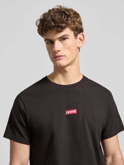 Männermodel trägt T-Shirt mit Label-Detail von Levi's®, schwarz, reine Baumwolle, Relaxed Fit, Nahaufnahme Oberkörper.