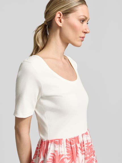 Frauenmodel trägt tailliertes Freizeitkleid aus Baumwoll-Mix von Tom Tailor in Weiß und Rosa mit Allover-Muster, Nahaufnahme Oberkörper.