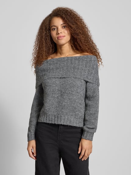 Modelka kobieca nosi szary melanżowy Regular Fit Strickpullover mit Woll-Anteil Modell 'SHINE' od Only z długim rękawem, sweter dzianinowy, dekolt carmen, tekstura grubo dziergana, widok całej sylwetki z przodu.