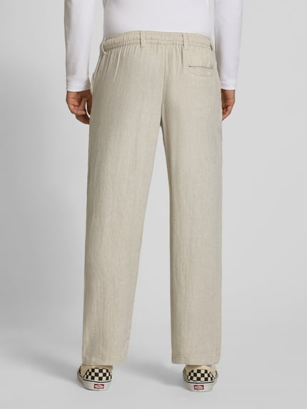 Männermodel trägt Leinenhose mit Bindegürtel Modell 'KARL MYKONOS' von Jack & Jones, relaxed fit, linnen-viscose mix, zandkleur, detail van Franse steekzakken en achtersteekzakje, bundwijdte M 41 cm, binnenbeenlengte M 78 cm, knoop- en ritssluiting, ganzkörperansicht rückansicht.