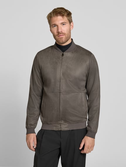 Männermodel trägt Regular Fit Bomberjacke mit Stehkragen von Christian Berg Men in Braun, elastischer Material-Mix, Ganzkörperansicht von vorne.