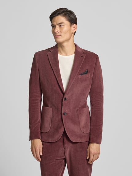 Männermodel trägt Slim Fit Sakko aus Baumwoll-Mix in Cord-Optik Modell 'Nick' von Zuitable in Rot, Struktur sichtbar, Ganzkörperansicht von vorne. Reverskragen, Brusttasche, aufgesetzte Taschen, 2-Knopfleiste. Rückenlänge 72 cm, Schulterbreite 45 cm, Ärmellänge 67 cm.
