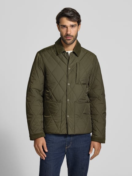Männermodel trägt Steppjacke mit Umlegekragen aus Cord Modell 'BENJA' von Casual Friday in Olivgrün, geometrische Steppung, Knopfleiste, Eingrifftaschen, Ganzkörperansicht von vorne. Rückenlänge 70 cm, Schulterbreite 48 cm, Brustweite 59 cm, Ärmellänge 67 cm.