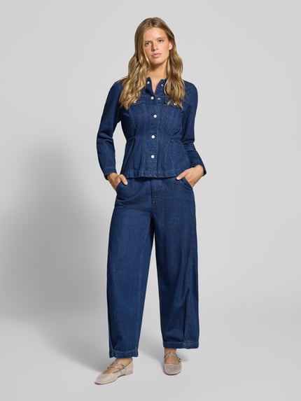 Frauenmodel trägt Flared Fit Jeansbluse aus Baumwoll-Lyocell-Mix von Marc O'Polo DENIM in dunklem Blau mit sichtbarer Knopfleiste, Ganzkörperansicht von vorne.