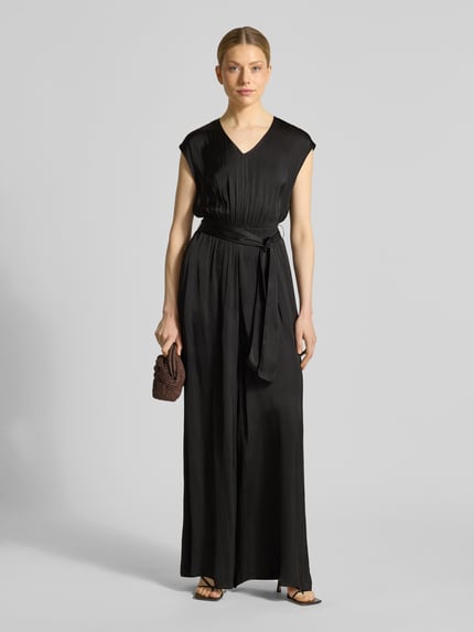Kobiece modelka nosi Regular Fit Jumpsuit mit Taillengürtel zum Binden od s.Oliver RED LABEL, efekt: jednolity kolor, krój regular fit, dekolt w serek, zamek błyskawiczny, bez rękawów, wpuszczane kieszenie, wykończenie materiału: satyna, całość w odcieniach czerni, satynowa powierzchnia, Ganzkörperansicht von vorne.