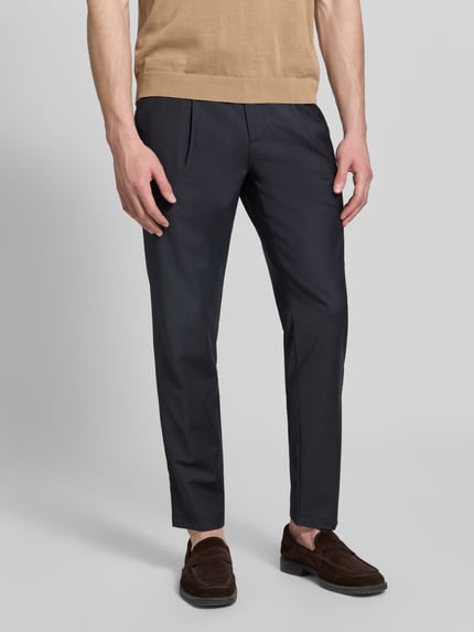 Männermodel trägt Straight Fit Stoffhose mit Woll-Anteil von g1920 in Dunkelblau mit Bundfalten, Eingrifftaschen, Haken-Reißverschluss, Nahaufnahme Unterkörper.
