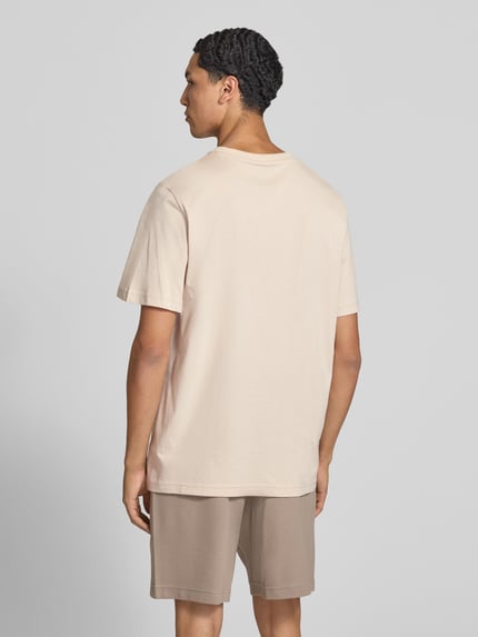 Männermodel trägt Regular Fit T-Shirt mit Logo-Stitching von PUMA PERFORMANCE in Beige, reine Baumwolle, Ganzkörperansicht Rückansicht.