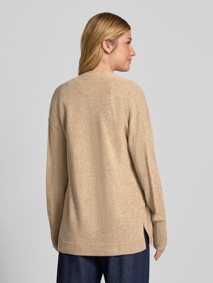 Frauenmodel trägt Strickjacke in offener Passform von Christian Berg Woman aus reiner Baumwolle, beige, gerippte Abschlüsse, Ganzkörperansicht Rückansicht.