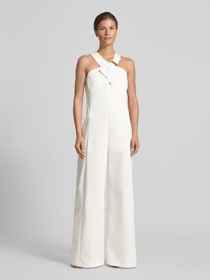 Modelka kobieca nosi Wide Fit Jumpsuit mit Zierschnalle od Rinascimento z białej bawełny, bez rękawów, krój wide fit, ozdobna klamra, szerokość w rozmiarze S: 40 cm, długość całkowita: 156 cm, długość nogawki wewnętrznej: 82 cm, widok całej sylwetki z przodu.