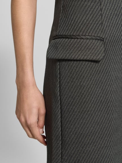 Kobiece modelka nosi spódnicę mini z mieszanki materiałów z dodatkiem wiskozy ICHI, efekt prążkowania, zamek błyskawiczny, kieszenie z patką, model 'KATE', kolor szaro-czarny, całkowita długość 49 cm, szerokość w rozmiarze S: 38 cm, detaliczny widok boczny.