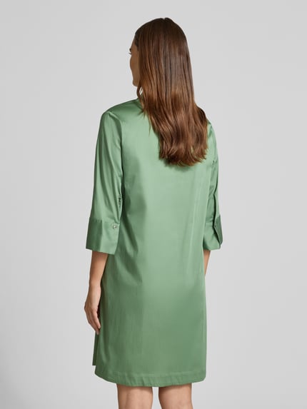 Frauenmodel trägt A-Linie Freizeitkleid aus Baumwoll-Mix von s.Oliver BLACK LABEL in mattem Grün mit glatter Struktur, Ganzkörperansicht Rückansicht.