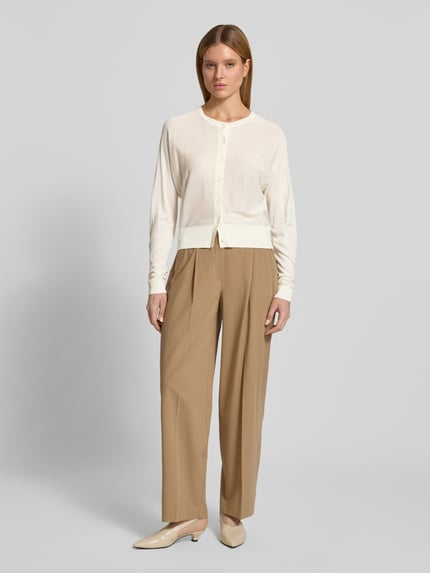 Frauenmodel trägt Strickjacke mit Rundhalsausschnitt Modell 'Desela' von OPUS im Viskose-Mix, Regular-Fit, Knopfleiste, beige, Ganzkörperansicht von vorne.