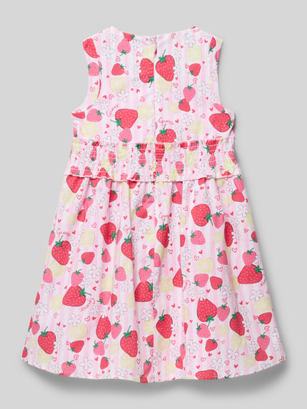 Dziewczynka nosi Regular Fit Kleid mit Logo-Detail Modell 'Poplin' od Guess, bawełniany materiał, kolorowy motyw owoców, krój regular fit, sukienka bez rękawów, całkowity widok z tyłu.