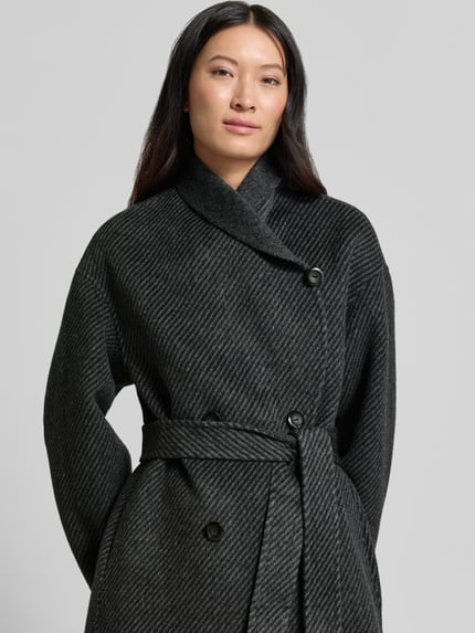 Frauenmodel trägt Mantel mit Schalkragen von Emporio Armani in dunklem Grau mit Taillienband, strukturierter Stoff, Nahaufnahme Oberkörper.
