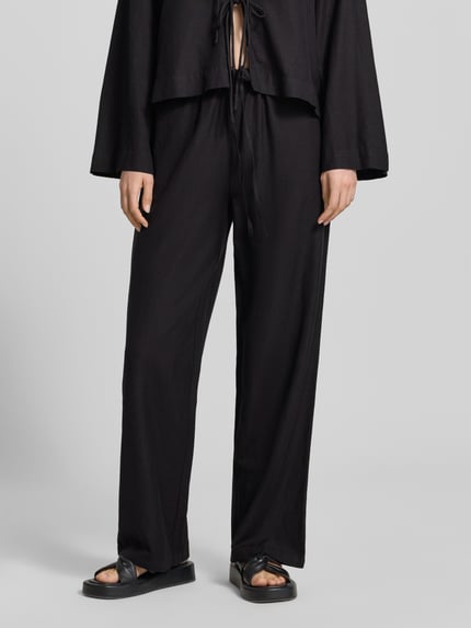 Frauenmodel trägt schwarze Damen Stoffhose aus Viskose-Mix mit Leinen-Viskose-Anteil, Wide-Leg-Pants, Eingrifftaschen, Tunnelzug, Modell 'PRISILLA' von Vila, Nahaufnahme Unterkörper, Kontext: Bundweite bei Größe 36: 35 cm, Innenbeinlänge bei Größe 36: 82 cm.