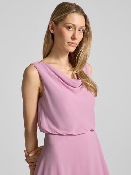 Frauenmodel trägt Knielanges Cocktailkleid mit Wasserfall-Ausschnitt von Christian Berg Cocktail aus Chiffon in Rosaton, Taillierter Schnitt, breite Träger, Wickeloptik am Saum, Haken- und Reißverschluss, Rückenlänge 120 cm bei Größe 36, Brustweite 45 cm bei Größe 36, Nahaufnahme Oberkörper.