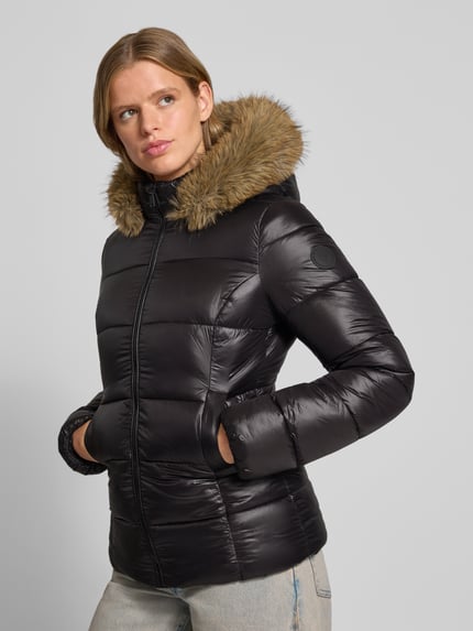 Frauenmodel trägt schwarze Steppjacke mit Kunstfell und Reißverschluss von REVIEW, wattierte Struktur, seitliche Eingrifftaschen, Nahaufnahme Oberkörper.