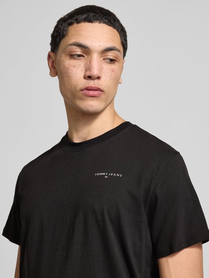 Männermodel trägt Slim Fit T-Shirt aus reiner Baumwolle Modell 'LINEAR CHEST TEE' von Tommy Jeans in Optik: Unifarben, Regular-Fit, Label-Print, Rundhals, Kurzarm, Material: reine Baumwolle; Nahaufnahme Oberkörper.
