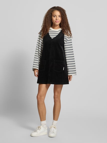 Frauenmodel trägt Minikleid aus Baumwoll-Mix von Marc O'Polo in Schwarz, unifarben, V-Ausschnitt, Cord, aufgesetzte Seitentaschen, Ganzkörperansicht von vorne.