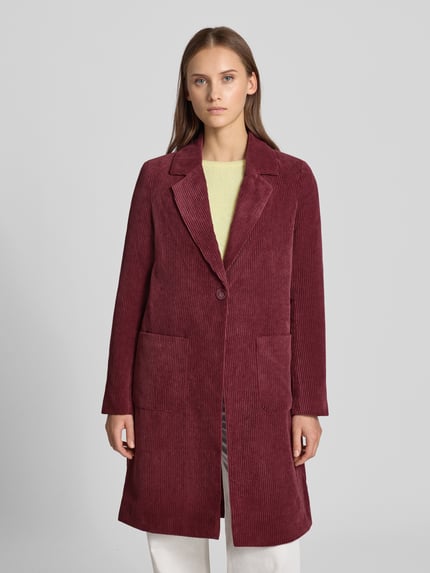 Frauenmodel trägt Regular Fit Mantel mit Reverskragen Modell 'ASTRID' von ONLY aus bordeauxfarbenem Cord, Vordertasche, Ganzkörperansicht von vorne.