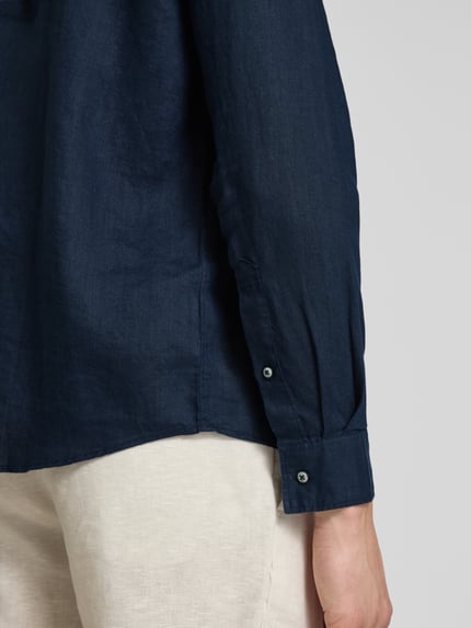 Männermodel trägt Regular Fit Freizeithemd aus reinem Leinen von s.Oliver RED LABEL in Dunkelblau, glatte Textur, Detailaufnahme rechter Ärmel.