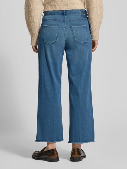 Frauenmodel trägt Wide Fit Jeans-Culotte aus Baumwoll-Mix Modell 'DREAM' von MAC in Blau mit ausgefranstem Beinabschluss, Ganzkörperansicht Rückansicht, elastischer Baumwoll-Modal-Mix, 5-Pocket-Design, verkürzte Passform, rückseitiges Label-Patch.