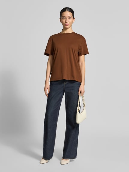 Frauenmodel trägt T-Shirt mit Rundhalsausschnitt von Stefanel in Braun, reine Baumwolle, gerader Schnitt, kombiniert mit Jeans, Ganzkörperansicht von vorne.