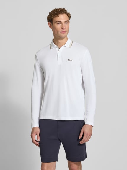 Männermodel trägt weißes Regular Fit Poloshirt aus reiner Baumwolle Modell 'Plisy' von BOSS, dezenter Logo-Schriftzug, Ganzkörperansicht von vorne, Herren Poloshirt von BOSS.