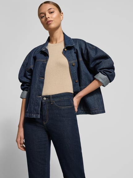 Frauenmodel trägt Feminine Fit Jeans in verkürzter Passform von Marc Cain in Dunkelblau, glatte Baumwoll-Elasthan-Textur, Nahaufnahme Oberkörper.